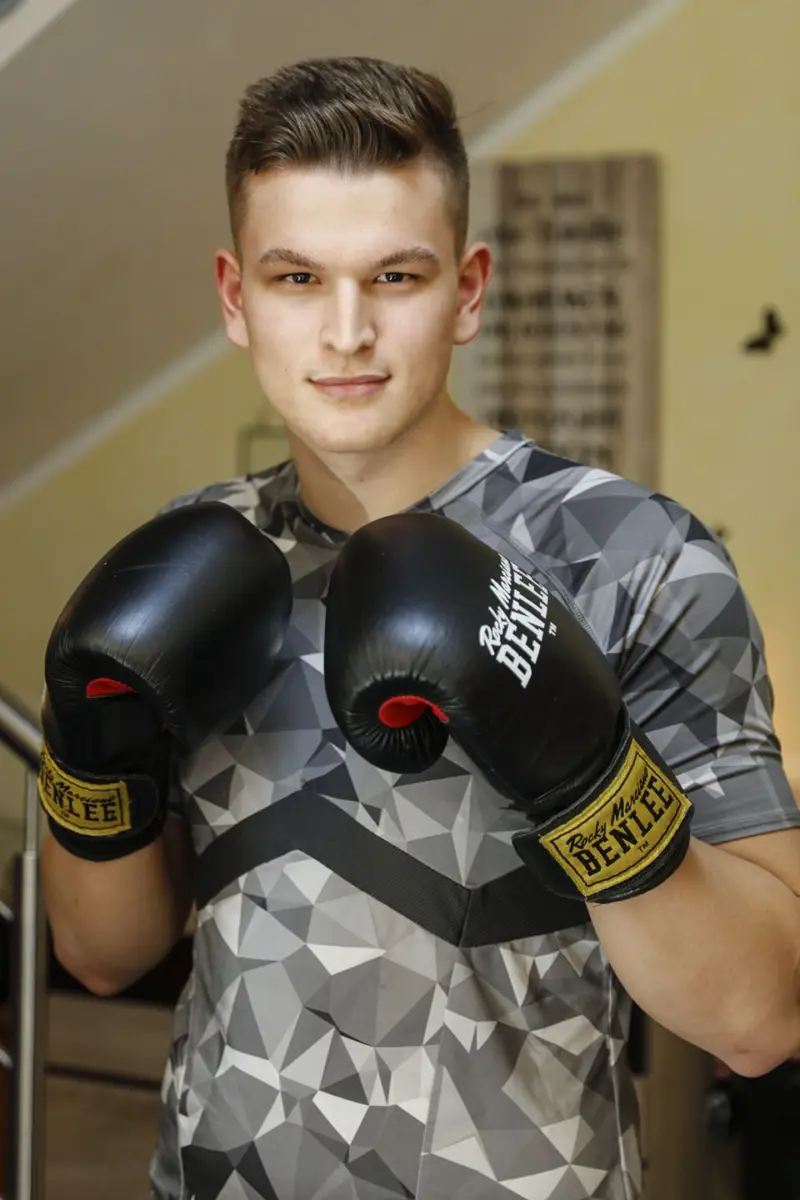 Ein junger Mann mit Boxhandschuhe steht da in einer Kampfstellung.