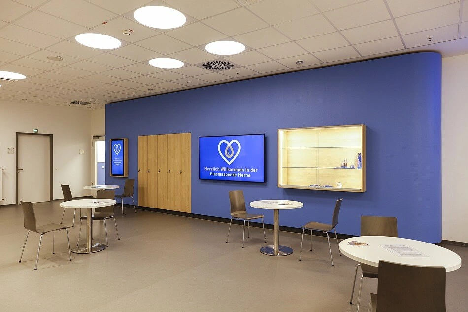 Ein Warteraum mit Tischen und Stühlen in einem Plasmaspendezentrum.