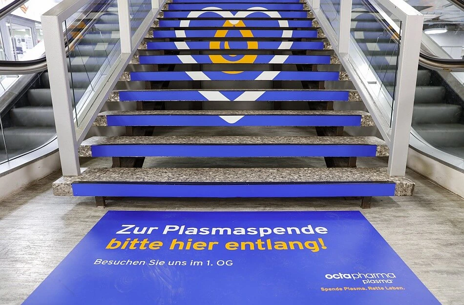 Eine blaue Treppe mit den Logo von "Octapharma Plasma" - ein Herz mit einem Tropfen.