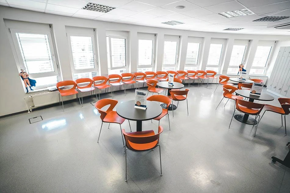 Ein Warteraum mit Tischen und Stühlen in einem Spendezentrum.