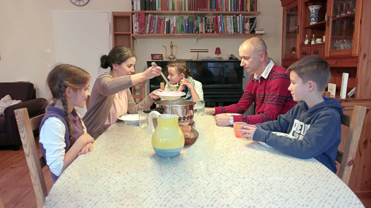 Eltern sitzen mit ihren Kindern an einem Tisch und essen.