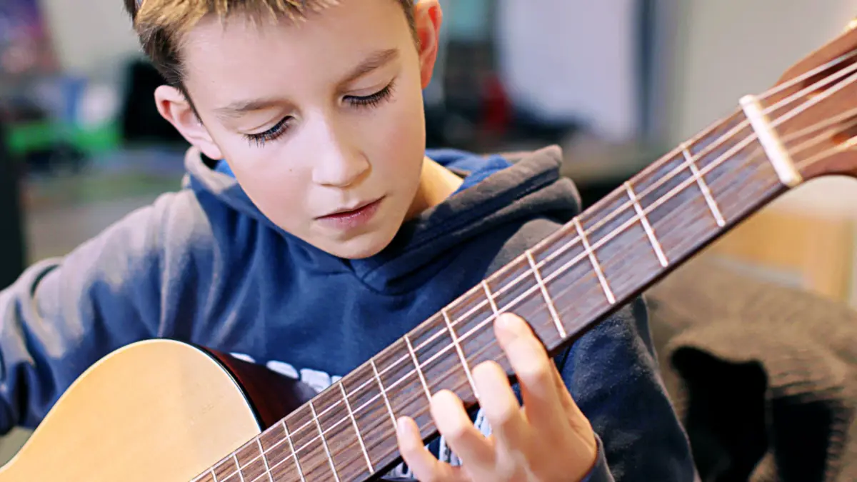 Ein Junge spielt konzentriert Gitarre.